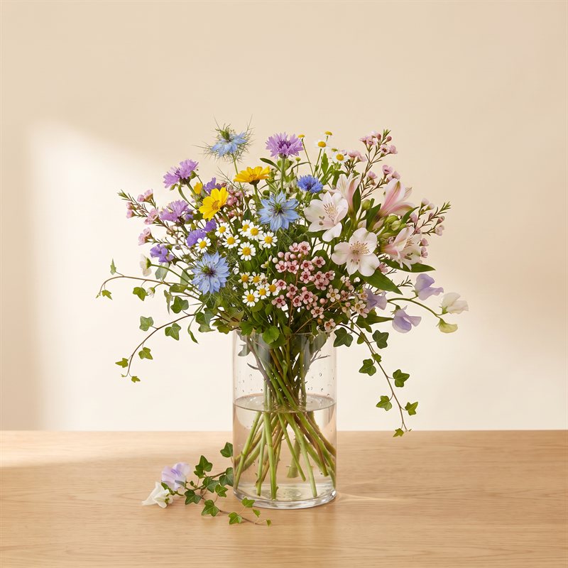 Garden-style arrangement with wild greenery in a clear vase