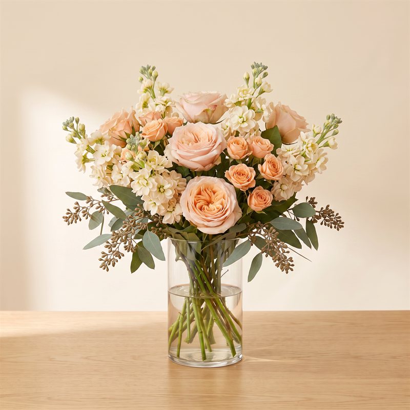 Peach and cream roses in a clear glass vase